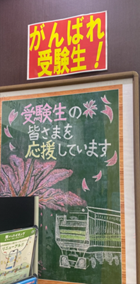 A handwritten encouragement message for exam takers displayed at a Japanese train station