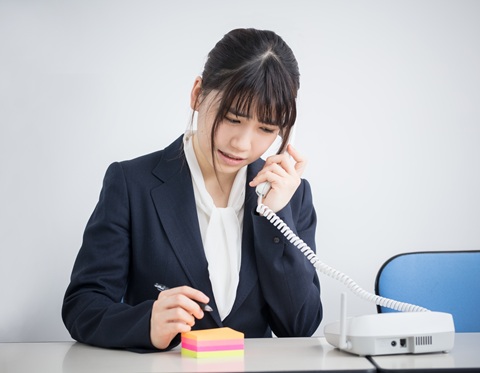 Japanese professional offering a polite apology with 'Sumimasen' in a modern office